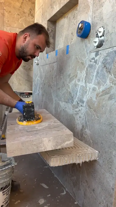 Alex, owner of DreamDim Remodeling, installing a floating marble shower bench