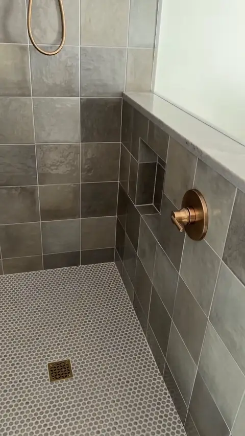 Walk-in shower with penny-tile floor and brass drain