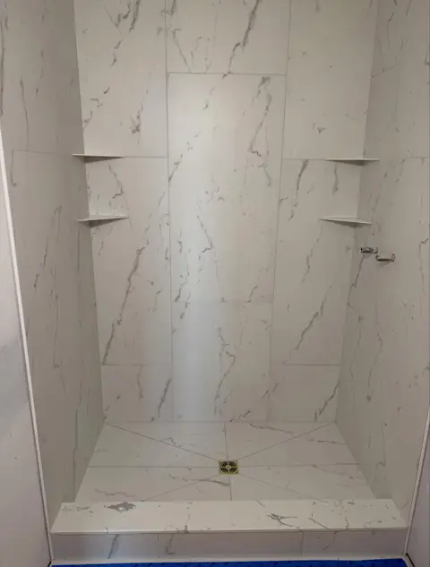 Large-format marble-look shower with corner shelves